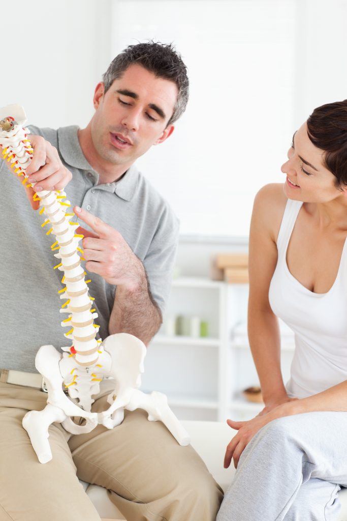 Urgent care chiropractor explaining a spine model to patient